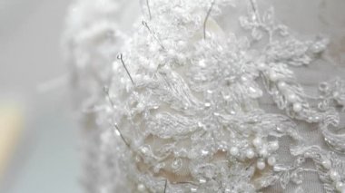 Yakın çekim moda tasarımcısı stüdyosunda gelinler için iğne dantel gelinlik sabitler. Terzi özel bir gelinlik oluşturur. Pins ve iğneler anahat ile güvenli. Küçük özel işletme