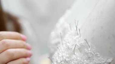 Yakın çekim moda tasarımcısı stüdyosunda gelinler için iğne dantel gelinlik sabitler. Terzi özel bir gelinlik oluşturur. Pins ve iğneler anahat ile güvenli. Küçük özel işletme