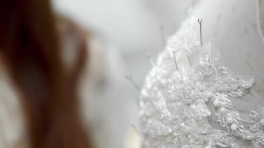 Yakın çekim moda tasarımcısı stüdyosunda gelinler için iğne dantel gelinlik sabitler. Terzi özel bir gelinlik oluşturur. Pins ve iğneler anahat ile güvenli. Küçük özel işletme