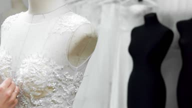 Yakın çekim moda tasarımcısı stüdyosunda gelinler için iğne dantel gelinlik sabitler. Terzi özel bir gelinlik oluşturur. Pins ve iğneler anahat ile güvenli. Küçük özel işletme
