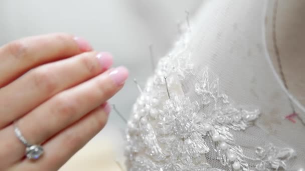 Close-up designer de moda para noivas em seu estúdio pinos agulhas vestido de noiva rendas. Seamstress cria um vestido de noiva exclusivo. Seguro com alfinetes e agulhas delinear. Pequenas empresas privadas — Vídeo de Stock