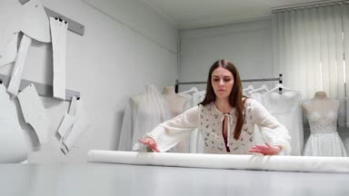 Giysi Tasarımcısı studio tablo üzerinde ölçümler ile çalışıyor. 4 k Uhd vurdu. Tatlı beyaz ve açık renkli dikiş yavaş beyaz kumaş skein dağıtın. el yapımı terzilik