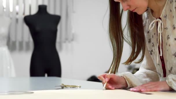 Hermosa chica diseñadora de moda se basa en las plantillas de papel para cortar la tela en los maniquíes vestidos con vestidos de novia. Fabricante de vestidos de novia . — Vídeo de stock