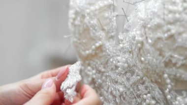 Yakın çekim moda tasarımcısı stüdyosunda gelinler için iğne dantel gelinlik sabitler. Terzi özel bir gelinlik oluşturur. Pins ve iğneler anahat ile güvenli. Küçük özel bir iş. Dikmek