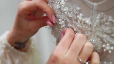 Yakın çekim moda tasarımcısı stüdyosunda gelinler için iğne dantel gelinlik sabitler. Terzi özel bir gelinlik oluşturur. Pins ve iğneler anahat ile güvenli. Küçük özel bir iş. Dikmek