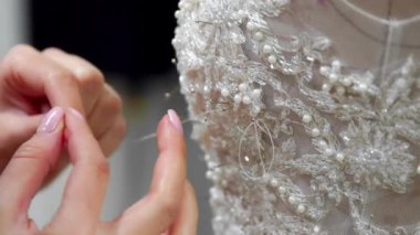 Yakın çekim moda tasarımcısı stüdyosunda gelinler için iğne dantel gelinlik sabitler. Terzi özel bir gelinlik oluşturur. Pins ve iğneler anahat ile güvenli. Küçük özel bir iş. Dikmek
