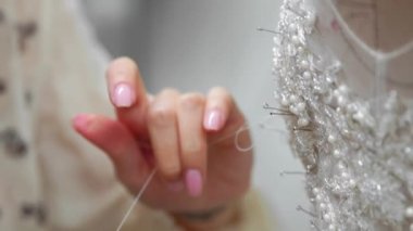 Yakın çekim moda tasarımcısı stüdyosunda gelinler için iğne dantel gelinlik sabitler. Terzi özel bir gelinlik oluşturur. Pins ve iğneler anahat ile güvenli. Küçük özel bir iş. Dikmek