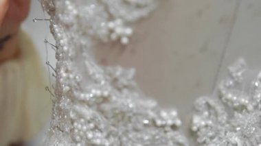 Yakın çekim moda tasarımcısı stüdyosunda gelinler için iğne dantel gelinlik sabitler. Terzi özel bir gelinlik oluşturur. Pins ve iğneler anahat ile güvenli. Küçük özel bir iş. Dikmek