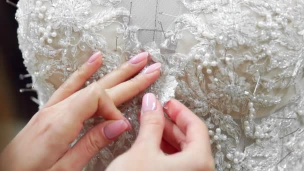 Γκρο πλαν σχεδιαστής μόδας για τη νύφη στο στούντιο του καρφίτσες βελόνες νυφικό από δαντέλα. Μοδίστρα δημιουργεί ένα αποκλειστικό νυφικό. Ασφαλής με καρφίτσες και βελόνες διάρθρωσης. Μικρή ιδιωτική επιχείρηση. Ράβω — Αρχείο Βίντεο
