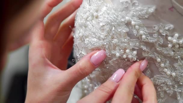 Close-up fashion designer for brides in his Studio pins needles lace wedding dress. Seamstress creates an exclusive wedding dress. Secure with pins and needles outline. Small private business. Sew — Stock Video