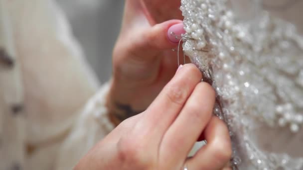 Primer plano diseñador de moda para novias en su Studio pins agujas vestido de novia de encaje. Costurera crea un vestido de novia exclusivo. Asegure con alfileres y agujas contorno. Pequeña empresa privada. Coser — Vídeo de stock