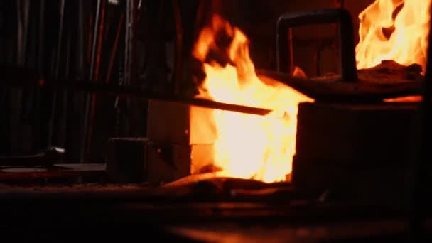 Close-up van een smid wakkeren de vlammen van de oven, met behulp van de tools voorkomt sintels, vonken vliegen naar de kant in slow motion. Close-up van smeden hand. — Stockvideo