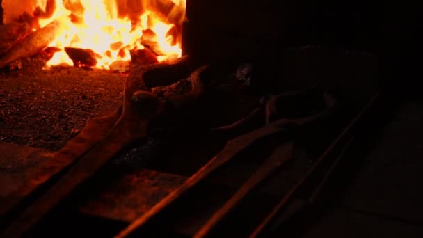 Close-up van een smid wakkeren de vlammen van de oven, met behulp van de tools voorkomt sintels, vonken vliegen naar de kant in slow motion. Close-up van smeden hand. — Stockvideo