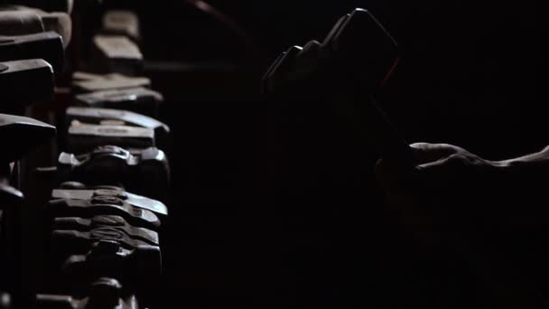 Gros plan d'une main d'homme robuste prend un marteau métallique sur un fond sombre au ralenti. Smith prend son marteau à main pour travailler le métal 