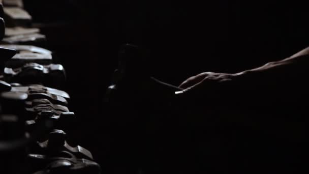 Close-up van een mans hand gooit een hamer en draait het op een donkere achtergrond in de contour licht. Brutale, krachtige concept — Stockvideo