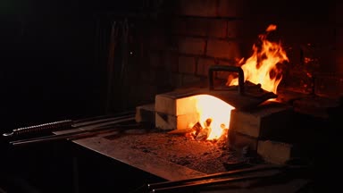 Bir demirci ocağı, alevler fanning araçları kullanarak closeup köz önler, uçan tarafa ağır çekimde kıvılcım. Demirci el Close-Up.