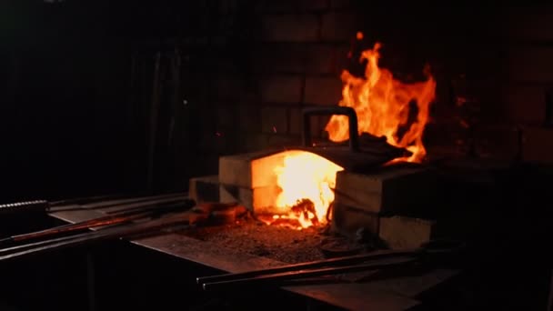 Close-up van een smid wakkeren de vlammen van de oven, met behulp van de tools voorkomt sintels, vonken vliegen naar de kant in slow motion. Close-up van smeden hand. — Stockvideo
