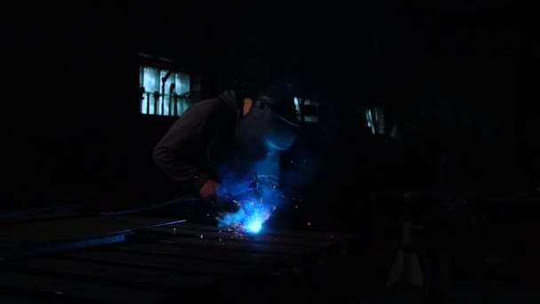 Il saldatore lavora con una maschera al rallentatore. Le scintille volano in direzioni diverse. Saldatura a bagliore di colore blu. Lavorare con materiali in acciaio — Video Stock