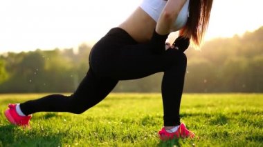 İnce atletik kadın diz-bounce egzersiz veya lunges yapıyor Park'ta çalışma dışarı. Çim pembe spor ayakkabı günbatımı ayak yakın çekim
