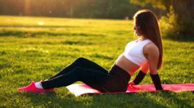 Genç ve güzel bir kadın onun fitness egzersiz tatilinde mindere oturuyor. Ağır çekimde saç düzeltme güneş ışığı altında egzersiz sonrası dinlenme. Arka ışık saç.