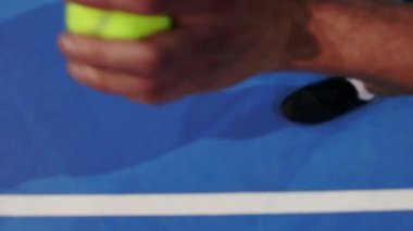 Topu tutan ve hizmet hazırlanıyor tenisçi. Yakın çekim ayak tenis oyuncusu hizmet vermeye hazırlanıyor. Mahkeme topa vurma ve raket isabet.