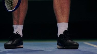 Topu tutan ve hizmet hazırlanıyor tenisçi. Yakın çekim ayak tenis oyuncusu hizmet vermeye hazırlanıyor. Mahkeme topa vurma ve raket isabet.