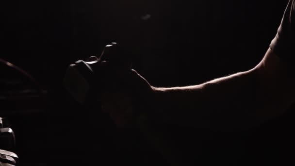 Close-up of a mans hand throws a hammer and rotates it on a dark background in the contour light. Brutal powerful concept — Stock Video