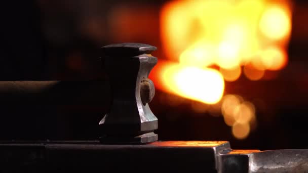 Primo piano di un martello fabbro sullo sfondo delle fiamme ardenti del forno . — Video Stock
