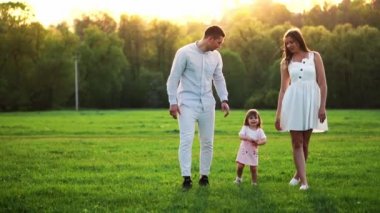 Mutlu genç aile yaz sahada yürüyüş çocuk ile. Sağlıklı anne, baba ve küçük kızı kız doğanın keyfini birlikte, açık havada. Günbatımı.