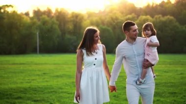 Mutlu genç aile yaz sahada yürüyüş çocuk ile. Sağlıklı anne, baba ve küçük kızı kız doğanın keyfini birlikte, açık havada. Günbatımı.