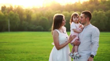 Mutlu genç aile yaz sahada yürüyüş çocuk ile. Sağlıklı anne, baba ve küçük kızı kız doğanın keyfini birlikte, açık havada. Günbatımı.
