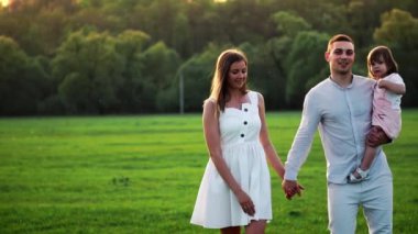 Mutlu genç aile yaz sahada yürüyüş çocuk ile. Sağlıklı anne, baba ve küçük kızı kız doğanın keyfini birlikte, açık havada. Günbatımı.