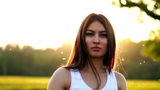 Joven hermosa mujer escuchando música en el parque mientras corre. Retrato de chica deportiva sonriente con auriculares mirando a la cámara en el parque en otoño. Mujer atleta mirando a la cámara durante el atardecer de invierno . — Vídeos de Stock