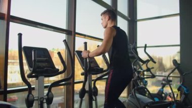 Spor salonunda eliptik çapraz antrenör eğitimi almadan önce portre fitness adamı ısınıyor. Spor salonunda çapraz antrenör üzerine yakın çekim erkek kardiyo egzersizi..