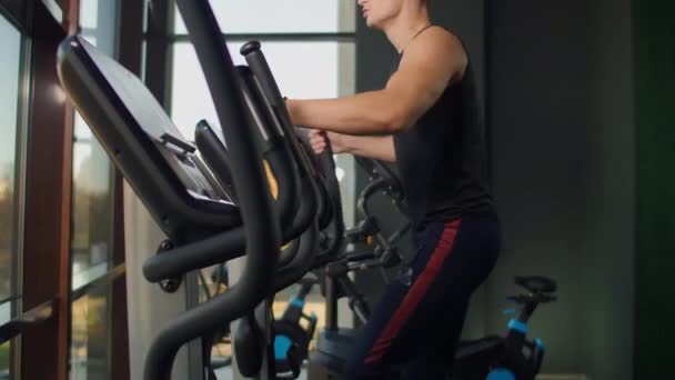 Portrait fitness homme échauffement avant l'entraînement sur vélo elliptique dans le club de gym. Gros plan entraînement cardio-training masculin sur cross trainer en fitness . — Video