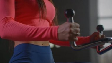 Mükemmel vücut için spor salonunda dairesel antrenman. Güzel, genç, beyaz bir kadın spor salonunda kürek çekmekten yoruldu. Hem de ağır çekimde..