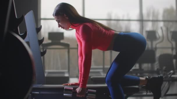 Mujer estudiante está haciendo ejercicio con mancuerna en el gimnasio — Vídeo de stock