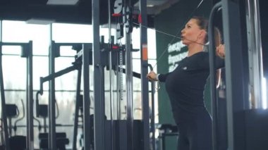 Genç bir kadın spor salonunda dairesel bir eğitim yapıyor.