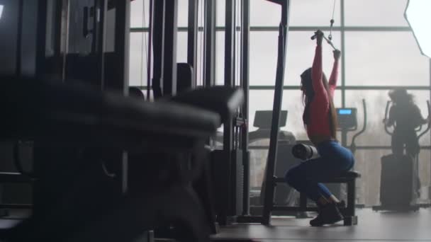 Bra träning på morgonen i gymmet. Träning i ett rum med stora fönster i bakgrunden en kvinna använder en ellipsoid och ett löpband — Stockvideo