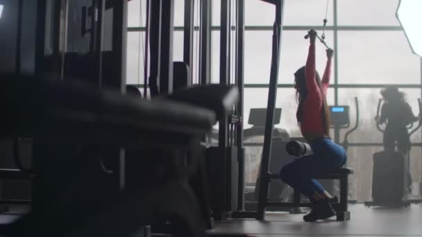 Goede training in de ochtend in de sportschool. Training in een ruimte met grote ramen op de achtergrond een vrouw gebruikt een ellipsoïde en een loopband — Stockvideo