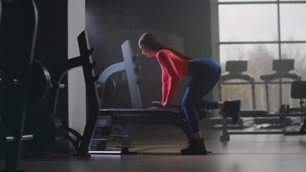 La joven está entrenando a su espalda en el banco — Vídeo de stock