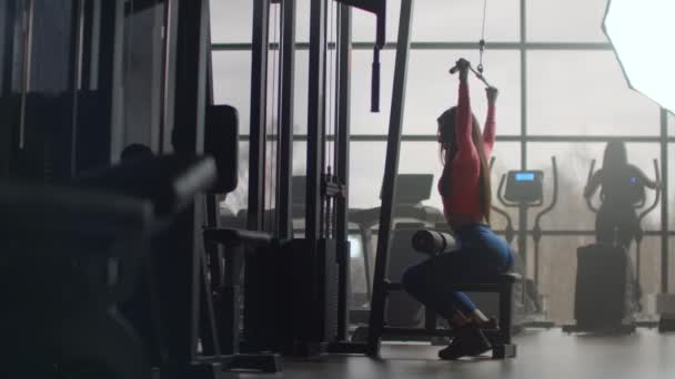 Machtstraining 's morgens in de sportschool. Training in een ruimte met grote ramen op de achtergrond een vrouw gebruikt een ellipsoïde en een loopband — Stockvideo