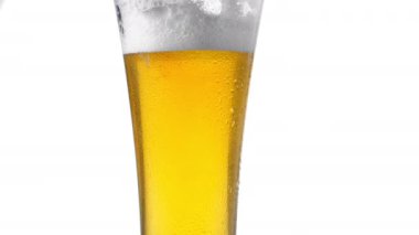 Arka plan beyazını köpüklerle kapatın. Bardakta bira, düşük açılı yan görüş, yavaş çekim..