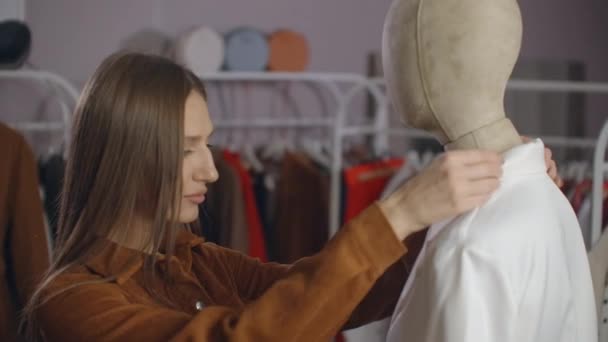 A young brunette looks at a clothing store dressed on a mannequin. Clothing store in the supermarket. Brand clothing in a boutique girl looks at a mannequin. — Stock Video