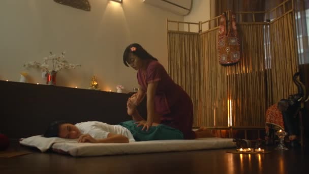 Asian Woman effectue un massage thaï traditionnel à la belle femme européenne. Réadaptation et traitement après blessures avec l'aide du massage. Se détendre et se reposer du massage des jambes, des bras et du dos . — Video