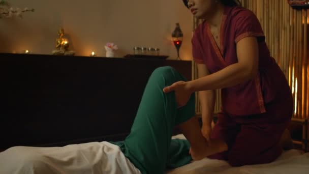 Asyalı kadın güzel Avrupalı kadına geleneksel Tayland masajı yapıyor. Masaj 'ın yardımıyla yaralardan sonra rehabilitasyon ve tedavi. Rahatlayın ve Bacak, Kollar ve Sırt masajından dinlenin. — Stok video