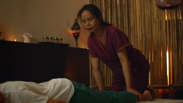 Asian Woman utför traditionell thailändsk massage till vacker europeisk kvinna. Rehabilitering och behandling efter skador med hjälp av massage. Slappna av och vila från massage av ben, armar och rygg. — Stockvideo