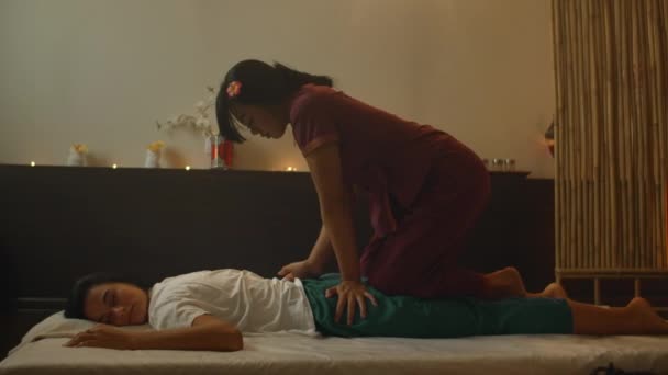 Aziatische vrouw voert traditionele Thaise massage aan mooie Europese vrouw. Revalidatie en behandeling na verwondingen met behulp van Massage. Ontspan en rust na massage van benen, armen en rug. — Stockvideo