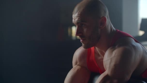 Hombre guapo haciendo bíceps levantando la barra en el banco en un gimnasio — Vídeo de stock