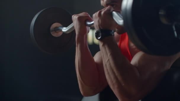 Síla tréninkové rameno biceps s činkou. Slim silný muž s velkými svaly zvedne činku sedí v tělocvičně na lavičce